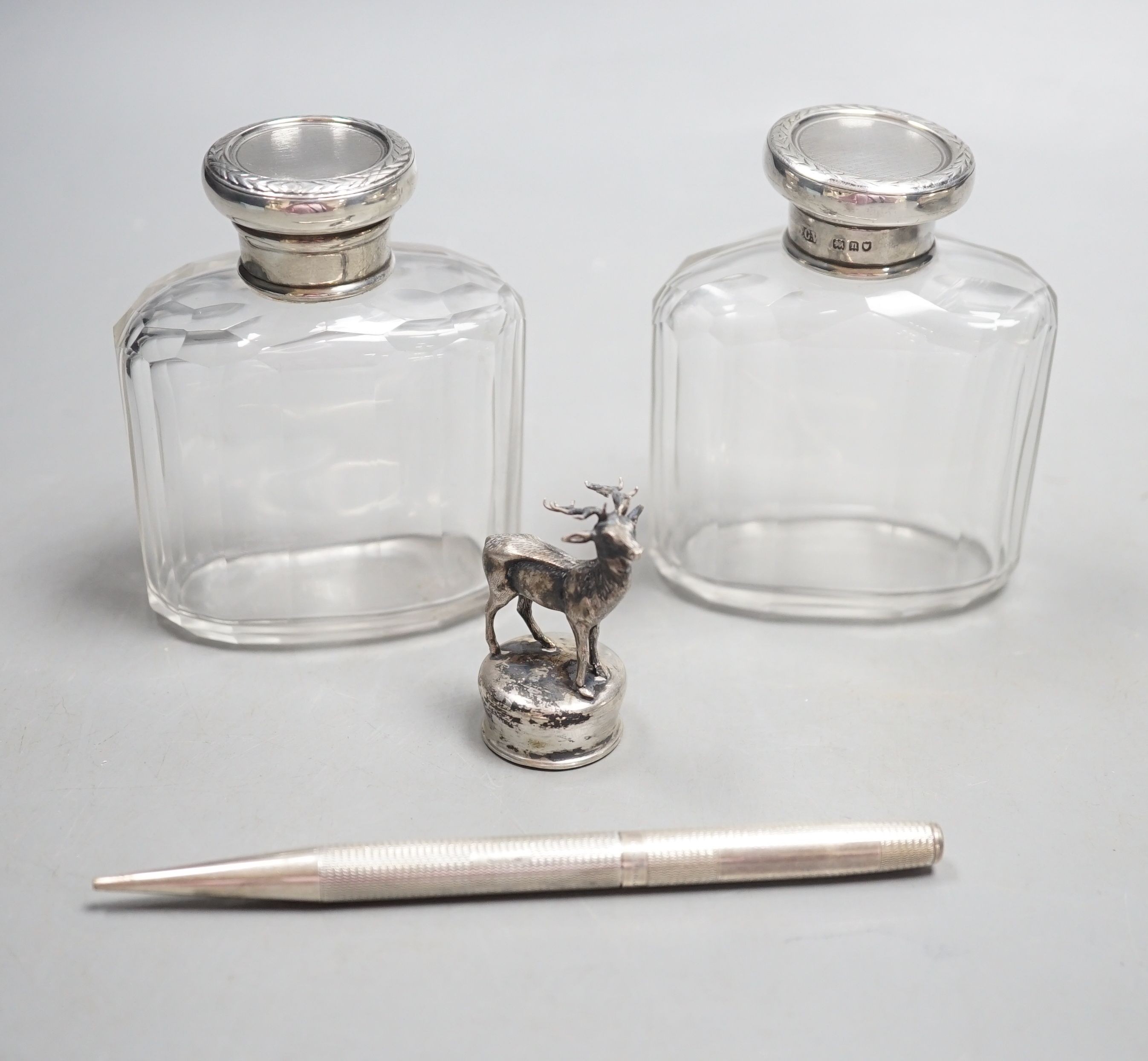 A white metal stag mounted bottle top,48mm, a pair of Edwardian silver topped glass toilet jars and a silver propelling pencil.